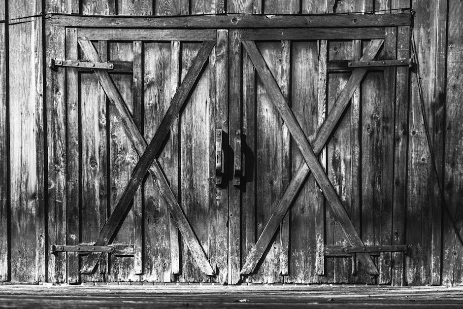 A detailed black and white image of rustic wooden barn doors, showcasing texture and vintage appeal.