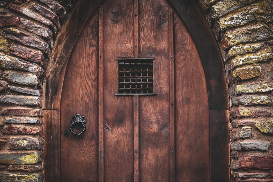 Close-up of a rustic wooden door embedded in a stone wall, featuring a vintage iron knocker.