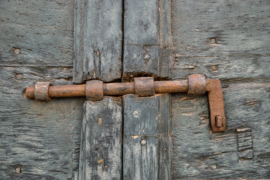 Detailed shot of a corroded iron bolt lock on a weathered wooden door.